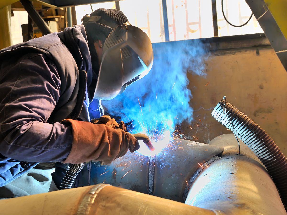 Technician using a welding fume extraction system with extraction arm capturing welding fumes