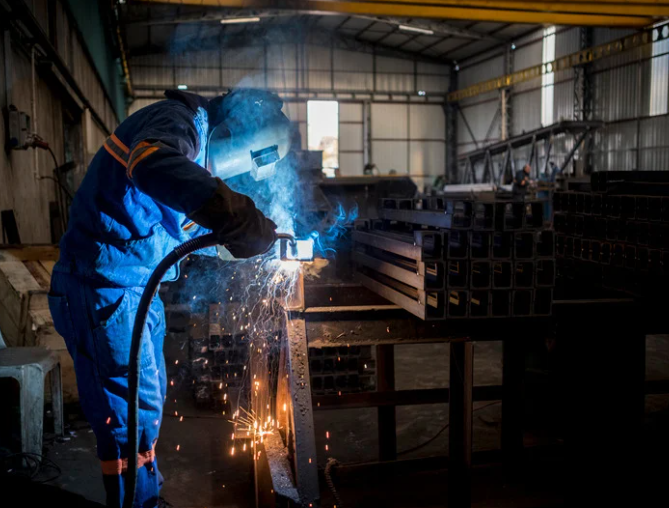 Welding fumes surrounding industrial equipment while a welding fume extraction system captures airborne contaminants