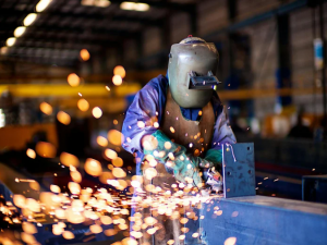Welder performing welding in a manufacturing facility while wearing protective safety equipment